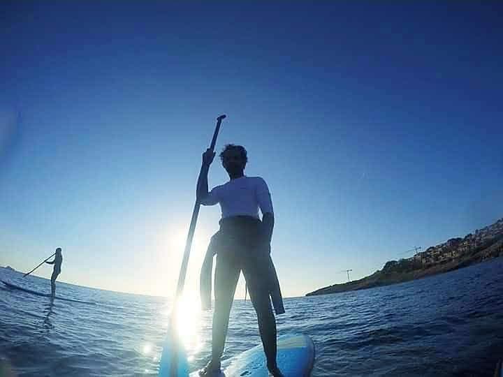 Stand-up paddleboarding silhouetted against the sun