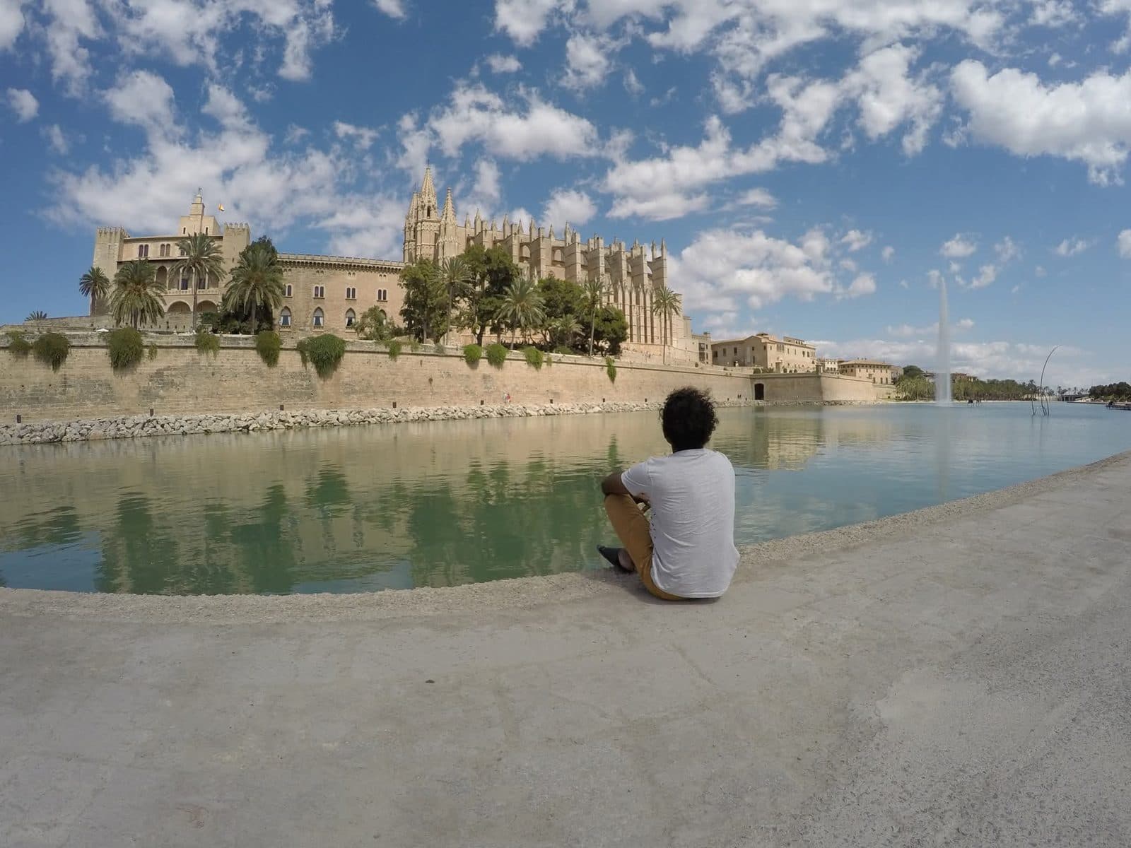 Ramesh sitting by the water in front of Palma Cathedral