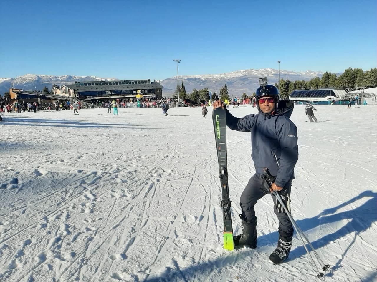Ramesh posing with skis on a snowy slope